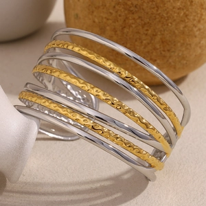 Détail d'un bracelet manchette ondulé multicouche plaqué or et argent sur décor