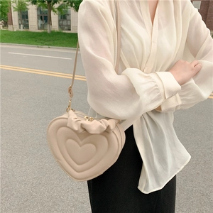 Chic beige heart-shaped crossbody bag with quilted layers and ruffled top handle