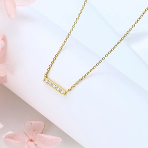 Detail of gold square pendant necklace with clear zircon stones on a white pedestal