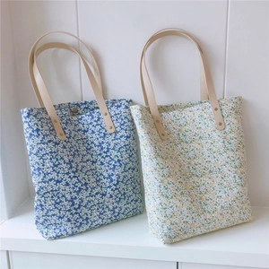 Close-up of floral canvas tote bags with elegant leather handles and metal rivet details