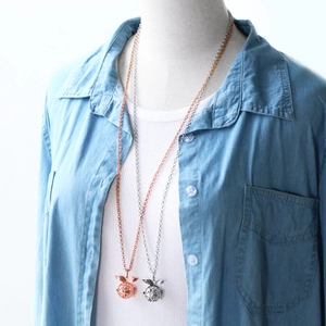 Locket necklace with wing design in rose gold and silver shown on a mannequin