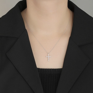 Classic 925 sterling silver cross necklace with pavé diamonds worn on elegant black blazer