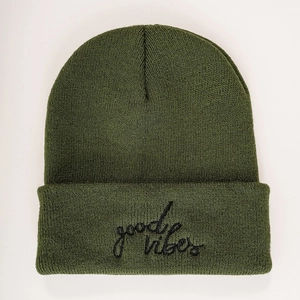 Detailed macro view of the dark green knit beanie with black good vibes embroidery