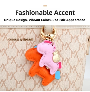 Detail of horse-shaped leather bag charms in pink and orange on a textured handbag