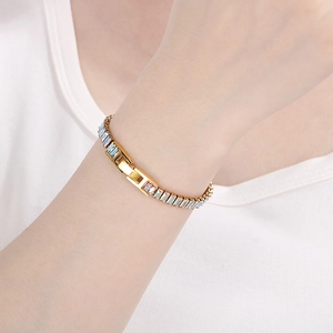 Detail of gold tennis bracelet featuring baguette-cut blue crystals and jewelry clasp