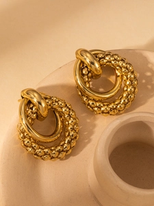 Close-up of gold double hoop earrings with textured beaded finish and smooth inner band