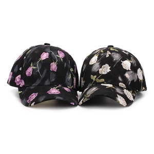 Détail de deux casquettes de baseball noires avec imprimés de roses vintage en violet et blanc