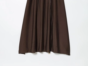 Détail de l'ourlet de robe plissée marron foncé avec cordon et embouts en métal doré