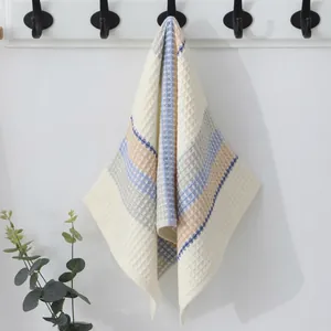Close-up of cream waffle weave cotton towel with blue and orange stripes on hook