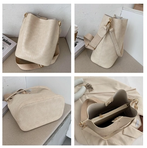 Detailsicht der beigen Eimer-Tasche mit Krokodil-Muster, breitem Gurt und Innentasche