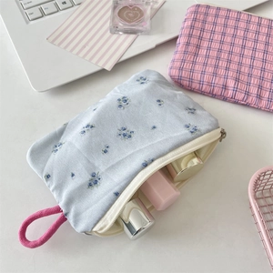 Blumige Kosmetiktasche und karierte Make-up-Tasche auf dem Schreibtisch mit Zubehör