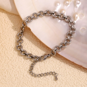 Detail of silver stainless steel chunky link anklet with lobster clasp on beige background