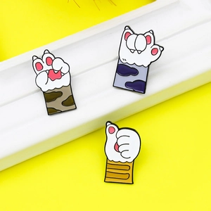 Three cute cat paw enamel pins in various colors displayed on a bright yellow background