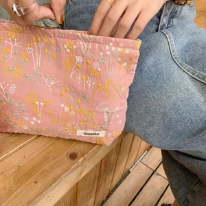 Detail of pink cotton fabric makeup bag with delicate yellow floral embroidery