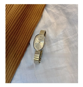 Detailed close-up of a silver ladies quartz watch with oval dial on textured fabric