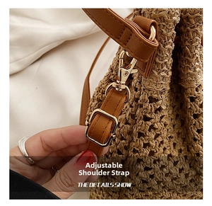Detail view of straw bucket bag featuring adjustable brown leather strap and gold buckle
