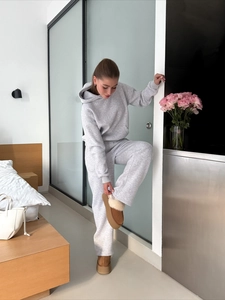 Women's grey slim fit hooded tracksuit set styled with plush platform boots in a cozy room