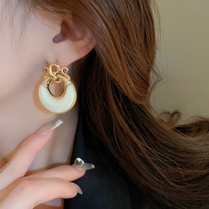 Close-up of vintage geometric knot earrings with white crescent pendants on model