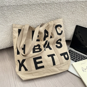 Detail of khaki canvas tote bag with black letter print in a minimalist home setting