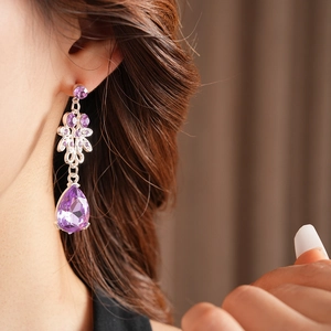 Close-up of vintage flower drop earring with purple zircon on female model