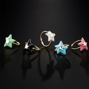 Five colored enamel star open rings in gold finish on a dark reflective surface
