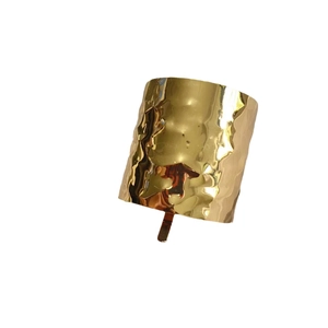 Wide gold hammered cuff bracelet with an irregular textured metallic surface design