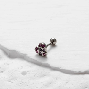 Macro shot of silver heart stud earring with pink and purple zircon stones on white stone