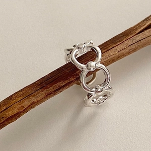 Detail of interlocking S925 sterling silver rings with delicate bead accents on driftwood