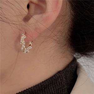 Close-up of pearl-wrapped gold C-shaped earrings on model for an elegant retro style