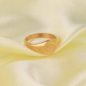 Detailed view of polished gold signet ring featuring a minimalist smiley face engraving