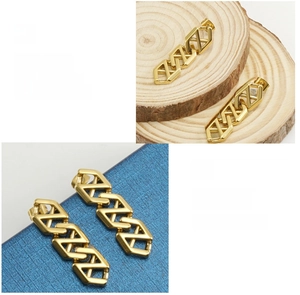 Detailed macro view of 18K gold-plated geometric hollow chain earrings on wooden background