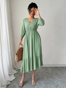 Détail de la robe verte à col en V avec texture à pois et ourlet à volants élégants