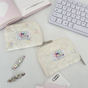 Detailed view of quilted cream pouches with floral embroidery and silver zipper closure