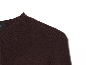 Detail of dark brown ribbed knit sweater showing crew neck and soft fabric texture