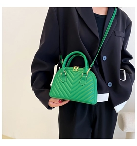 Close-up of vibrant green chevron quilted shell bag with gold zippers and slim strap