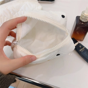 Détail de la trousse à maquillage matelassée blanche montrant un grand espace de rangement