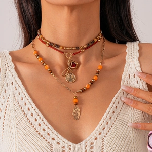 Detail of bohemian layered necklace with vintage beads and gold leaf pendant on model