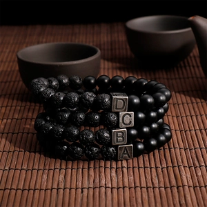 Set of four black lava stone and matte agate bracelets with vintage metal letter beads