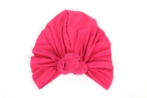 Detail of hot pink elastic turban hat with a signature knot design on white background
