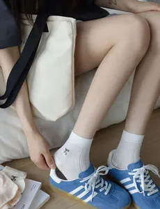 Close-up of white ribbed knit socks with black bow embroidery paired with blue sneakers