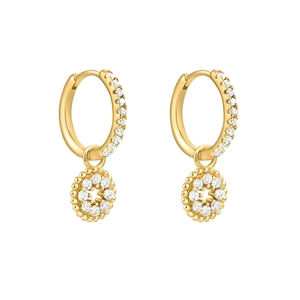 Détail de boucles d'oreilles créoles dorées avec zircons et pendentif floral