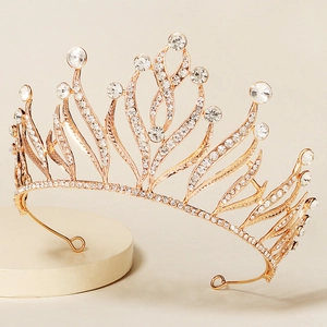Elegant gold bridal crown with crystal rhinestones and leaf motifs on a display stand