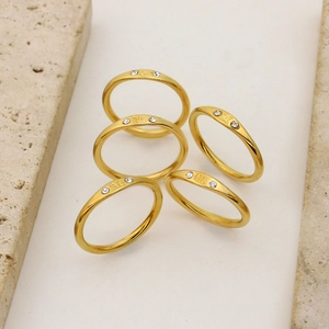 Close-up of five thin 18K gold-plated zodiac rings with diamonds and engraved signs