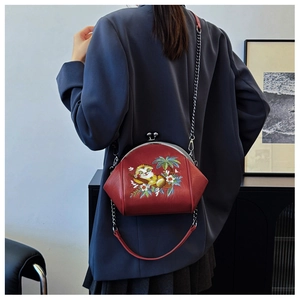 Close-up of a red embroidered shell bag featuring floral patterns and a metal chain strap