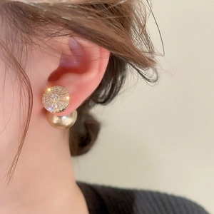 Detail of elegant gold-plated earring with radiant zircon and pearl jacket on model
