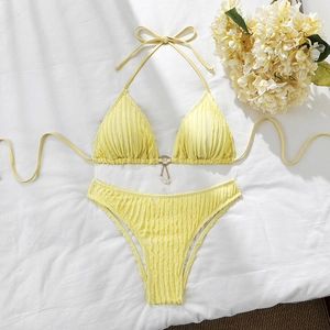 Detail of yellow bikini with wave texture and gold star tassel on white fabric
