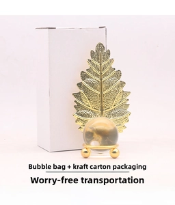 Close-up of golden leaf metal ornament with clear crystal ball and packaging box details