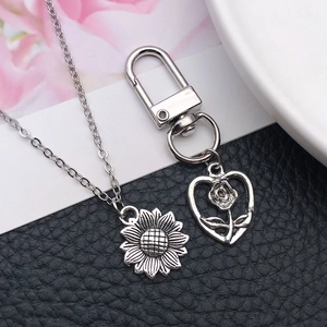 Set collana girasole argento antico e portachiavi rosa a cuore su pelle nera