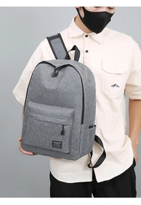 Close-up of a gray oxford laptop backpack worn by a model in a casual setting