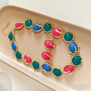 Parure de bijoux vintage dorés avec pierres ovales colorées sur plateau beige